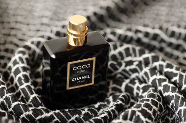 TERNOPIL, UKRAINE - SEPTEMBER 2, 2022 Coco Noir Chanel Paris worldwide famous french perfume black bottle on old plaid with monochrome pattern