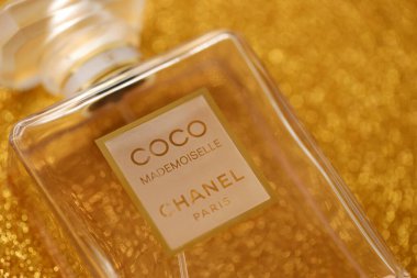 TERNOPIL, UKRAINE - SEPTEMBER 2, 2022 Coco Mademoiselle Chanel Paris worldwide famous french perfume bottle on shiny glitter background in golden and yellow colors