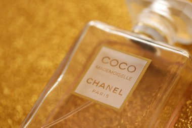TERNOPIL, UKRAINE - SEPTEMBER 2, 2022 Coco Mademoiselle Chanel Paris worldwide famous french perfume bottle on shiny glitter background in golden and yellow colors