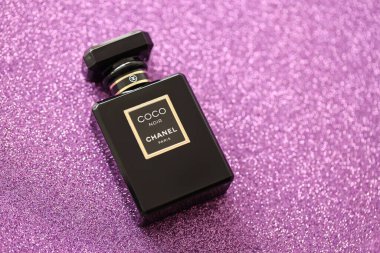 TERNOPIL, UKRAINE - SEPTEMBER 2, 2022 Coco Noir Chanel Paris worldwide famous french perfume black bottle on shiny glitter background in purple and pink colors
