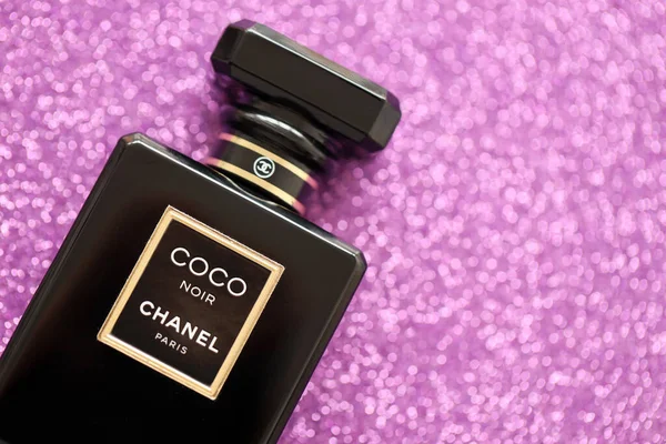 TERNOPIL, UKRAINE - SEPTEMBER 2, 2022 Coco Noir Chanel Paris worldwide famous french perfume black bottle on shiny glitter background in purple and pink colors