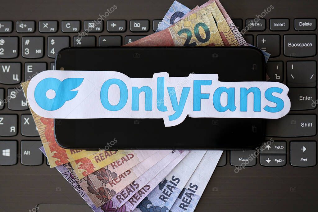 TERNOPIL, UKRAINE - SEPTEMBER 6, 2022 Onlyfans paper logotype on bunch of brazilian reals bills lies on black laptop keyboard buttons