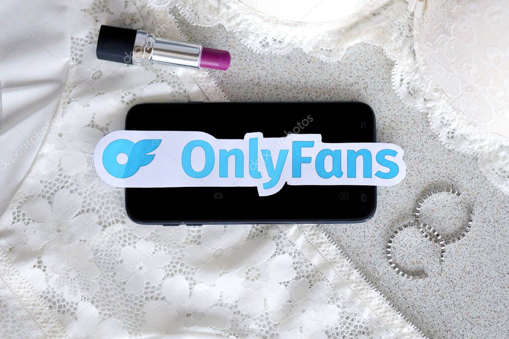 TERNOPIL, UKRAINE - SEPTEMBER 6, 2022 Onlyfans paper logotype among lipstick, earrings and women lingerie close to black smartphone