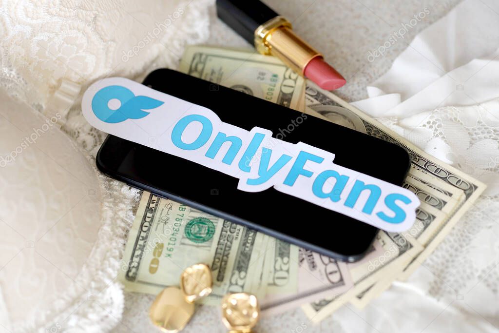 TERNOPIL, UKRAINE - SEPTEMBER 6, 2022 Onlyfans paper logotype among lipstick, earrings and women lingerie close to bunch of few US dollar bills