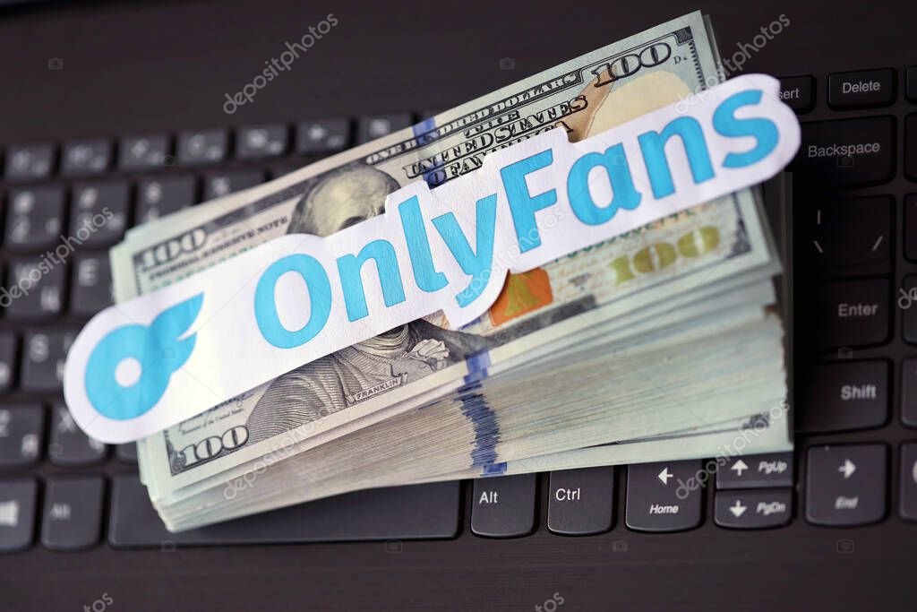 TERNOPIL, UKRAINE - SEPTEMBER 6, 2022 Onlyfans paper logotype on bunch of US dollar bills lies on black laptop keyboard buttons