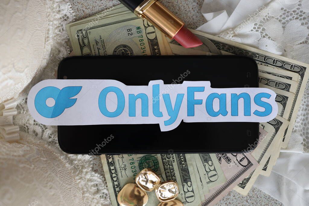 TERNOPIL, UKRAINE - SEPTEMBER 6, 2022 Onlyfans paper logotype among lipstick, earrings and women lingerie close to bunch of few US dollar bills