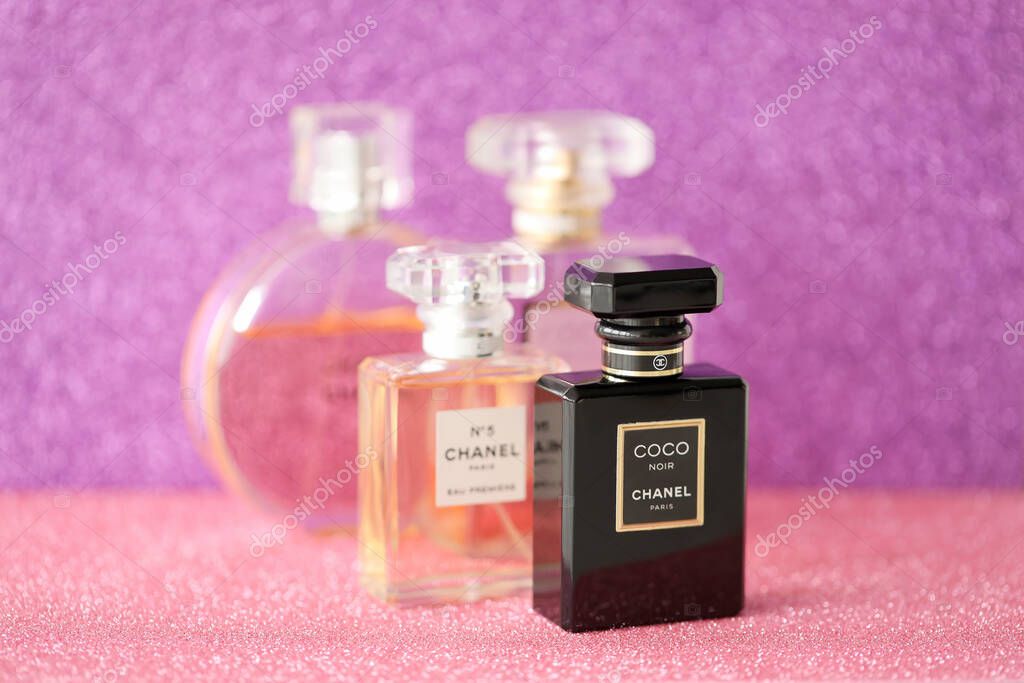 TERNOPIL, UKRAINE - SEPTEMBER 2, 2022 Chanel Coco Noir worldwide famous french perfume bottle among other perfumes on shiny glitter background in purple and pink colors