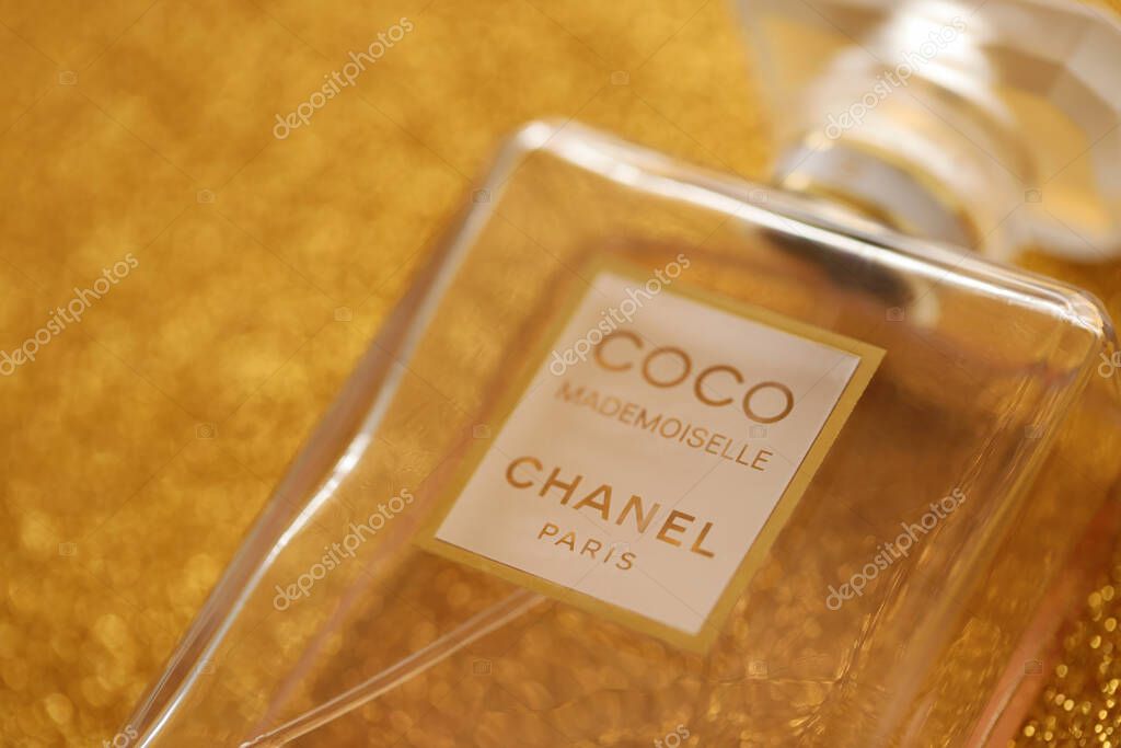 TERNOPIL, UKRAINE - SEPTEMBER 2, 2022 Coco Mademoiselle Chanel Paris worldwide famous french perfume bottle on shiny glitter background in golden and yellow colors