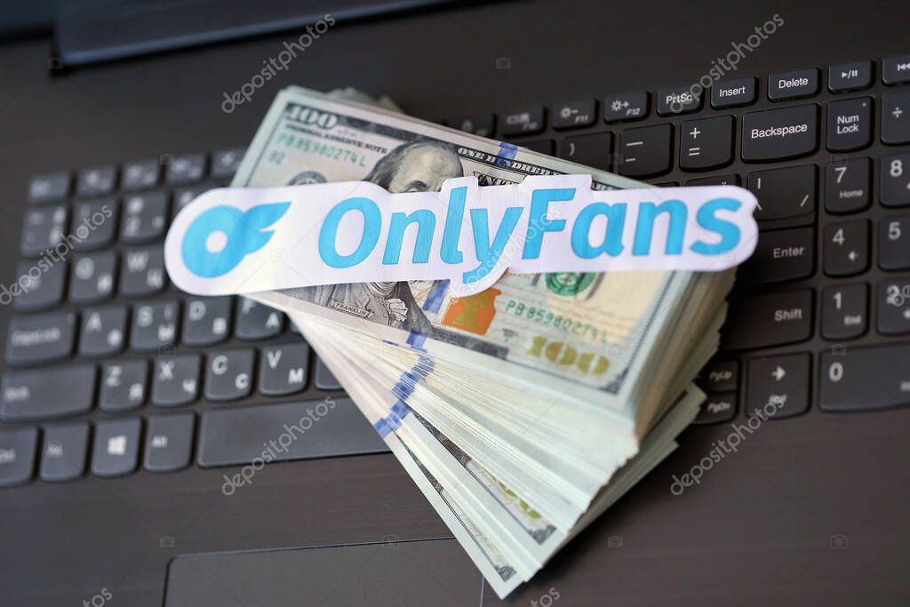 TERNOPIL, UKRAINE - SEPTEMBER 6, 2022 Onlyfans paper logotype on bunch of US dollar bills lies on black laptop keyboard buttons