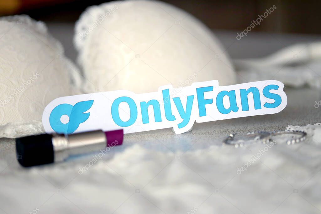 TERNOPIL, UKRAINE - SEPTEMBER 6, 2022 Onlyfans paper logotype among lipstick, earrings and women lingerie close up