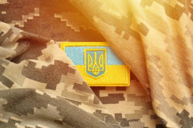 Ukrayna bayrağıyla pikselleştirilmiş dijital askeri kamuflaj kumaşı ve mavi ve sarı renkli sembollü arma. Ukrayna asker üniformasının nitelikleri