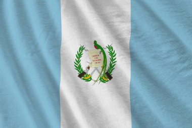 Guatemala bayrağı. Stüdyo ışıklarının altında büyük kıvrımlar sallanıyor. Resmi semboller ve renkler kumaş pankartıyla