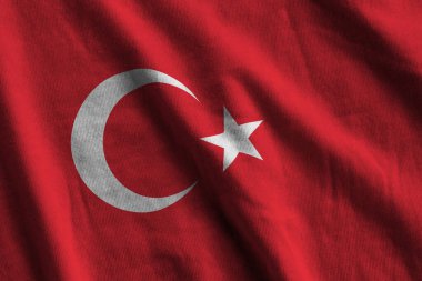 Stüdyo ışıklarının altında büyük kıvrımlı hindi bayrağı sallanıyor. Resmi semboller ve renkler kumaş pankartıyla