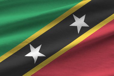 Saint Kitts ve Nevis bayrağı. Stüdyo ışıklarının altında büyük kıvrımlar sallanıyor. Resmi semboller ve renkler kumaş pankartıyla