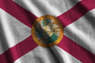 Florida eyaleti bayrağı. Stüdyo ışıklarının altında büyük kıvrımlar sallanıyor. Resmi semboller ve renkler kumaş pankartıyla