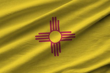 New Mexico eyaleti bayrağı. Stüdyo ışıklarının altında büyük kıvrımlar sallanıyor. Resmi semboller ve renkler kumaş pankartıyla