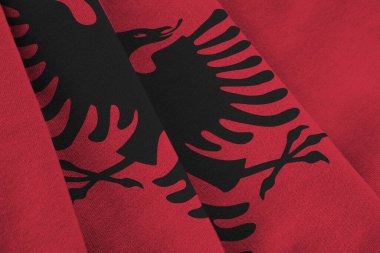 Arnavutluk bayrağı. Stüdyo ışıklarının altında büyük kıvrımlar sallanıyor. Resmi semboller ve renkler kumaş pankartıyla