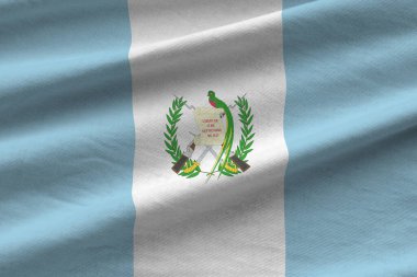Guatemala bayrağı. Stüdyo ışıklarının altında büyük kıvrımlar sallanıyor. Resmi semboller ve renkler kumaş pankartıyla