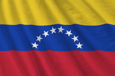 Büyük kıvrımlı Venezuela bayrağı stüdyo ışıklarının altında sallanıyor. Resmi semboller ve renkler kumaş pankartıyla