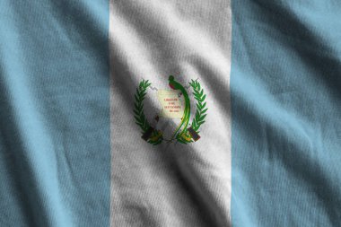 Guatemala bayrağı. Stüdyo ışıklarının altında büyük kıvrımlar sallanıyor. Resmi semboller ve renkler kumaş pankartıyla