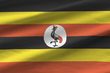 Stüdyo ışıklarının altında büyük kıvrımlı Uganda bayrağı sallanıyor. Resmi semboller ve renkler kumaş pankartıyla
