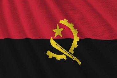 Büyük kıvrımlı Angola bayrağı stüdyo ışıklarının altında sallanıyor. Resmi semboller ve renkler kumaş pankartıyla