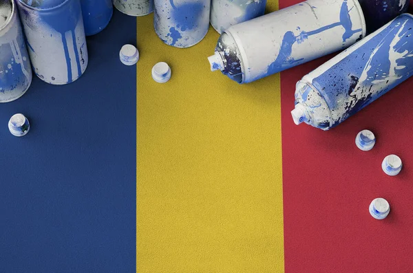 Romania flag and few used aerosol spray cans for graffiti painting. Street art culture concept, vandalism problems