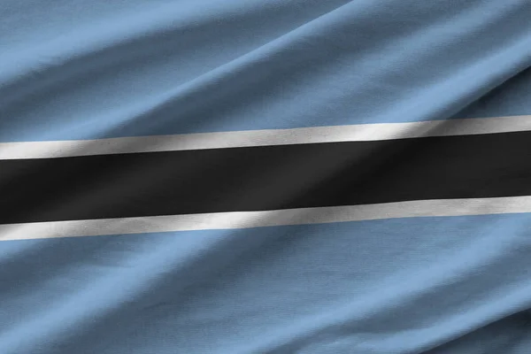 Botswana flag with big folds waving close up under the studio light indoors. The official symbols and colors in fabric banner
