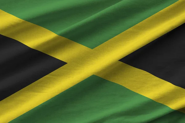 スタジオの照明の下で大きな折り目のあるジャマイカの旗が屋内で手を振っている ファブリックバナーの公式シンボルと色 — ストック写真