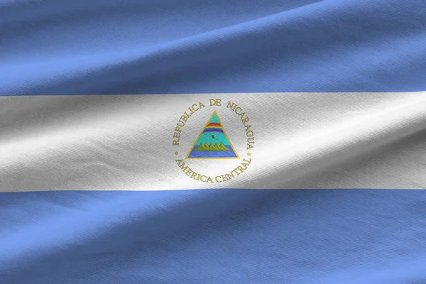 スタジオの光の下で屋内で手を振る大きな折り目のあるニカラグアの旗 ファブリックバナーの公式シンボルと色 — ストック写真