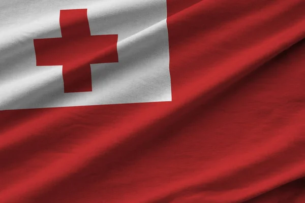 Tonga flag with big folds waving close up under the studio light indoors. The official symbols and colors in fabric banner