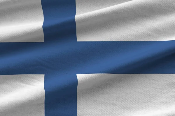 Finland flag with big folds waving close up under the studio light indoors. The official symbols and colors in fabric banner