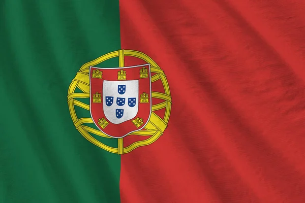 スタジオライトの下に大きな折り目の付いたポルトガルの旗が屋内で手を振っている ファブリックバナーの公式シンボルと色 — ストック写真