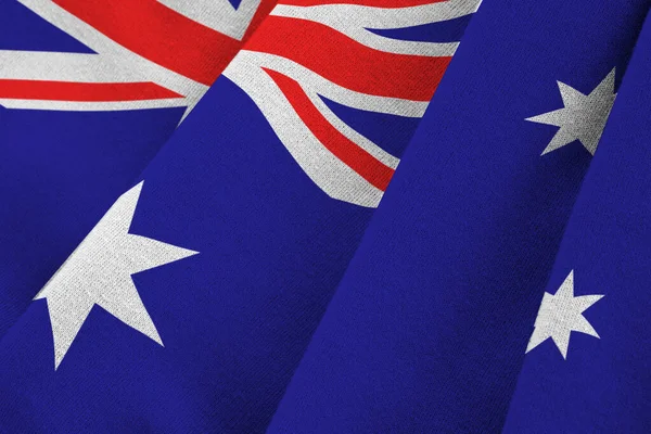 Australia flag with big folds waving close up under the studio light indoors. The official symbols and colors in fabric banner