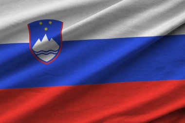 Büyük kıvrımlı Slovenya bayrağı stüdyo ışıklarının altında sallanıyor. Resmi semboller ve renkler kumaş pankartıyla
