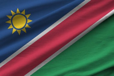 Büyük kıvrımlı Namibya bayrağı stüdyo ışıklarının altında sallanıyor. Resmi semboller ve renkler kumaş pankartıyla