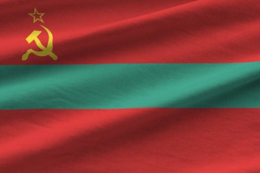 Büyük kıvrımlı Transnistria bayrağı stüdyo ışıklarının altında sallanıyor. Resmi semboller ve renkler kumaş pankartıyla