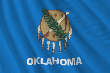 Oklahoma eyaleti bayrağı. Stüdyo ışıklarının altında büyük kıvrımlar sallanıyor. Resmi semboller ve renkler kumaş pankartıyla