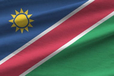 Büyük kıvrımlı Namibya bayrağı stüdyo ışıklarının altında sallanıyor. Resmi semboller ve renkler kumaş pankartıyla