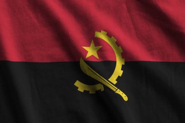 Büyük kıvrımlı Angola bayrağı stüdyo ışıklarının altında sallanıyor. Resmi semboller ve renkler kumaş pankartıyla