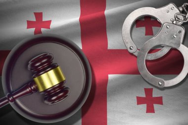 Karanlık odada yargıç tokmağı ve kelepçeli Georgia bayrağı. Suç ve ceza kavramı, suçlu konular için geçmiş