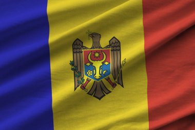 Büyük kıvrımlı Moldova bayrağı stüdyo ışıklarının altında sallanıyor. Resmi semboller ve renkler kumaş pankartıyla