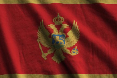 Stüdyo ışıklarının altında büyük kıvrımlı Karadağ bayrağı sallanıyor. Resmi semboller ve renkler kumaş pankartıyla