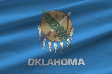 Oklahoma eyaleti bayrağı. Stüdyo ışıklarının altında büyük kıvrımlar sallanıyor. Resmi semboller ve renkler kumaş pankartıyla