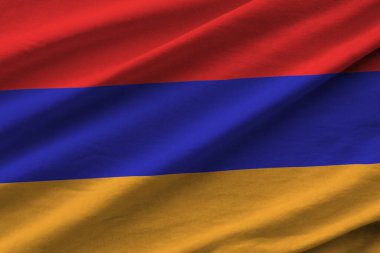 Büyük kıvrımlı Ermenistan bayrağı stüdyo ışıklarının altında sallanıyor. Resmi semboller ve renkler kumaş pankartıyla