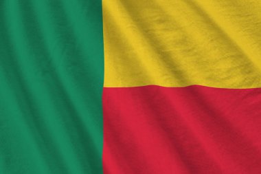 Stüdyo ışıklarının altında büyük kıvrımlı Benin bayrağı sallanıyor. Resmi semboller ve renkler kumaş pankartıyla