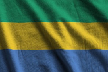 Büyük kıvrımlı Gabon bayrağı stüdyo ışıklarının altında sallanıyor. Resmi semboller ve renkler kumaş pankartıyla