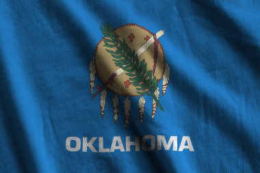 Oklahoma eyaleti bayrağı. Stüdyo ışıklarının altında büyük kıvrımlar sallanıyor. Resmi semboller ve renkler kumaş pankartıyla