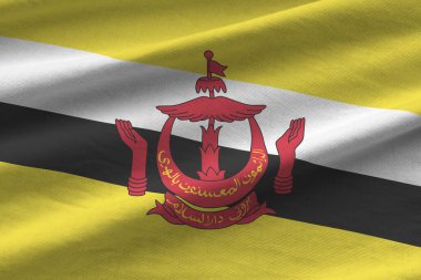 Brunei Darussalam bayrağı. Büyük kıvrımlı. Stüdyo ışıklarının altında sallanıyor. Resmi semboller ve renkler kumaş pankartıyla