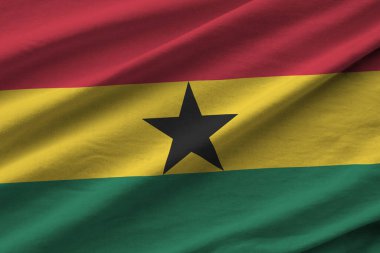 Büyük kıvrımlı Gana bayrağı stüdyo ışıklarının altında sallanıyor. Resmi semboller ve renkler kumaş pankartıyla